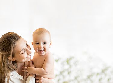 Young mother holds her smiling baby in her arms